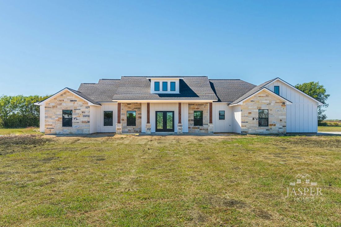 Custom stone modern farmhouse with cedar porch posts on acreage