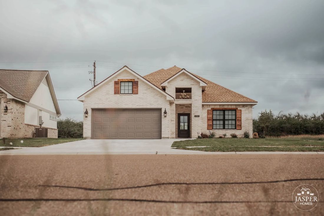 White brick home with cedar shutters and two-car garage